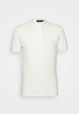 Polo blanc à manches courtes avec col, patte à deux boutons et petit logo brodé sur le côté gauche de la poitrine.