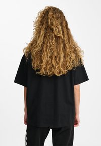 Zwarte oversized t-shirt met korte mouwen, gemaakt van katoen. Soepele textuur met een ontspannen pasvorm, zichtbare naden en geen zichtbare patronen of graphics.
