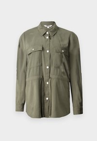 Olijfgroene shirt gemaakt van een zachte stof, met een knopenrij aan de voorkant, twee borstzakken met kleppen en lange mouwen.