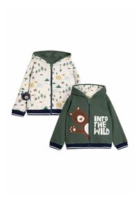 Zaļš zip-up kapucis ar lāča grafiku, ribotu tekstūru un baltu izsistību koku un kempinga elementu rakstu aizmugurējā pusē.