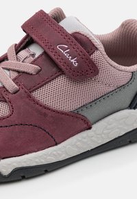 Bordowe i szare buty sportowe z siateczki i zamszu, z rzepem oraz teksturowaną gumową podeszwą z widocznymi wzorami.