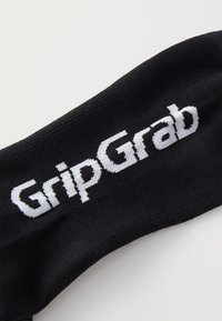 Czarna skarpetka z białym napisem "GripGrab" wyraźnie widocznym. Tkanina wydaje się gładka, z ciasno plecionym wzorem i bez dodatkowych elementów.