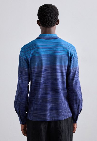 Mėlynos ombre spalvos ilgos rankovės marškiniai su horizontaliomis dryžiais, turintys apykaklę ir sagčių rankogalius, pagaminti iš lygios medžiagos su subtilia tekstūra.