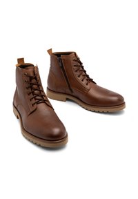Brązowe skórzane botki sięgające kostki z sznurówkami i zamkiem błyskawicznym z boku, teksturowana cholewa, beżowa podeszwa oraz wzmocnione detale szwów.
