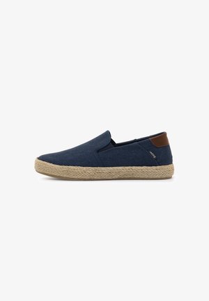 Zapato de slip-on azul marino con suela trenzada en tono beige y acento marrón en el talón, mostrado en perfil lateral sobre fondo blanco.
