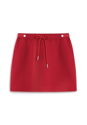 Falda deportiva roja hecha de una tela suave, con una cintura elástica y cordón, dos bolsillos laterales y accesorios metálicos.