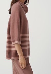 Vaaleanpunainen neulottu pusero kauluksella, puolipitkillä hihoilla, resorireunuksilla ja vaakasuunnassa tummanpunaisten raitojen koristama helma.