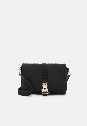 Sort quiltet crossbody-taske med guldlås og justerbar skulderrem på en ensfarvet baggrund.