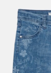 Ljusblå denimjeans med blommönster, femfickdesign och en metallnitar detalj på framsidan av fickan.