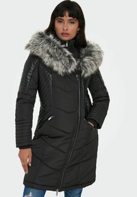Manteau matelassé noir avec un design matelassé, col en fausse fourrure et fermeture éclair. Comprend des poches zippées et des manches côtelées.