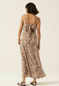 Kwiecowa sukienka maxi z lekkiego materiału, z wiązaniem z tyłu i wycięciami. Wzór dominuje w odcieniach żółtego, różowego i zielonego.
