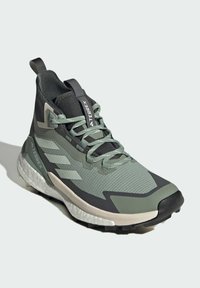 Groene en zwarte sportchoenen met een bovenwerk van mesh, rubberen zool, getextureerd ontwerp en gewatteerde enkelsteun. Voorzien van reflecterende accenten.