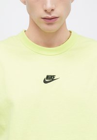 Ανοιχτό πράσινο βαμβακερό T-shirt με μαύρο λογότυπο Nike στο κέντρο. Κλασικό στρογγυλό λαιμόκο ψη και απαλή υφή.