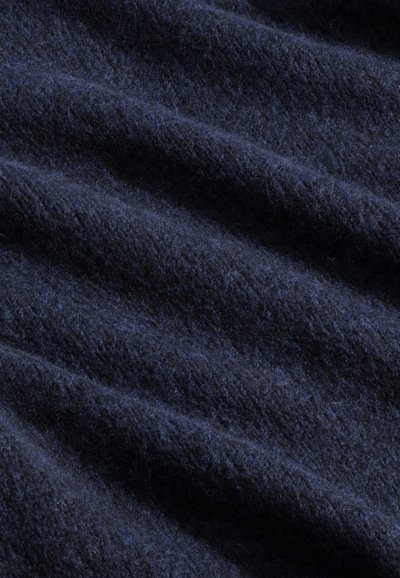 Tissu bleu marine, texturé avec des fils doux et duveteux. Le matériau présente de légères variations de teinte et de profondeur, créant une apparence ondulée.