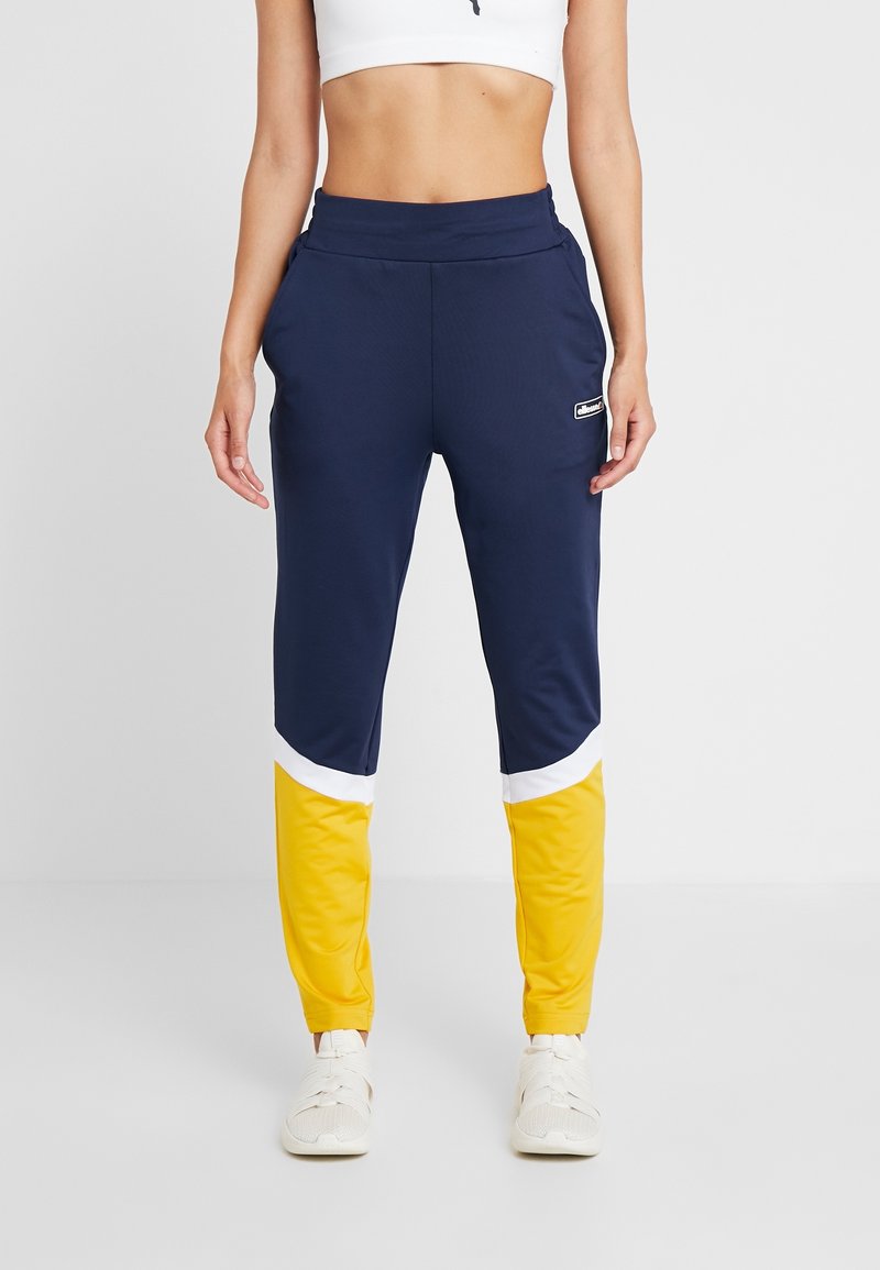 Marineblauwe joggings met gele en witte accenten op de onderbenen, gemaakt van een gladde, lichte stof. Voorzien van een elastische tailleband.