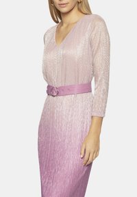 Długa, jasnoróżowa sukienka z gradientowym efektem ombre, z dekoltem w kształcie litery V, rękawami o długości trzy czwarte oraz pasującym szerokim paskiem z okrągłą klamrą.