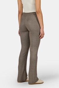 Rudos, raštuoti, išsiplėtę kelnės, pasižyminčios laisvu siluetu, su elastine juosta ir subtiliais siuvinėjimo akcentais šonuose. Matomi avalynė su guminiais padais.