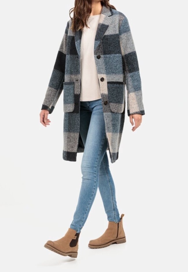 Wollen blend jas in blauw, grijs en zwart ruitpatroon met een kraag, twee voorkwakken en knoopsluiting. Gecombineerd met lichtblauwe jeans en bruine laarzen.