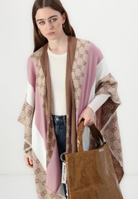 Strikket sjal med diagonale striber i pink, brun og hvid med et logo-mønster. Akkompagneret af en skinnende brun tote taske.