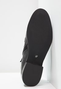 Zapato de cuero negro con parte superior texturizada y suela de goma negra. Talla 37 marcada en la suela, con cremallera lateral para facilitar el uso.