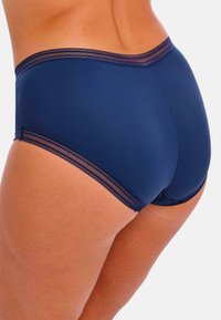 Marineblauwe slip met een gladde textuur, voorzien van kantaccenten bij de tailleband en beenopeningen voor extra detail en contrast.