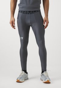 Szürke sportleggings rugalmas anyagból, széles derékpánttal, amelyen "ARMOUR" felirat és egy fehér logó található a bal combon.