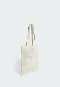 Bijela torba za nošenje izrađena od pletenog materijala s perforiranim uzorkom. Ima dugačke, ravne ručke i suptilan uzorak logotipa na prednjoj strani.