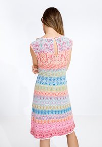 Abito a maglia caleidoscopico con maniche a cappuccio, modelli geometrici multicolori e apertura a chiave sul retro con dettaglio a pulsante.