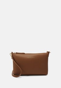 Hnědá kožená kabelka na ruku s texturovaným povrchem, zlatými zipy a odnímatelným popruhem. Na přední straně má decentně vyražené logo.