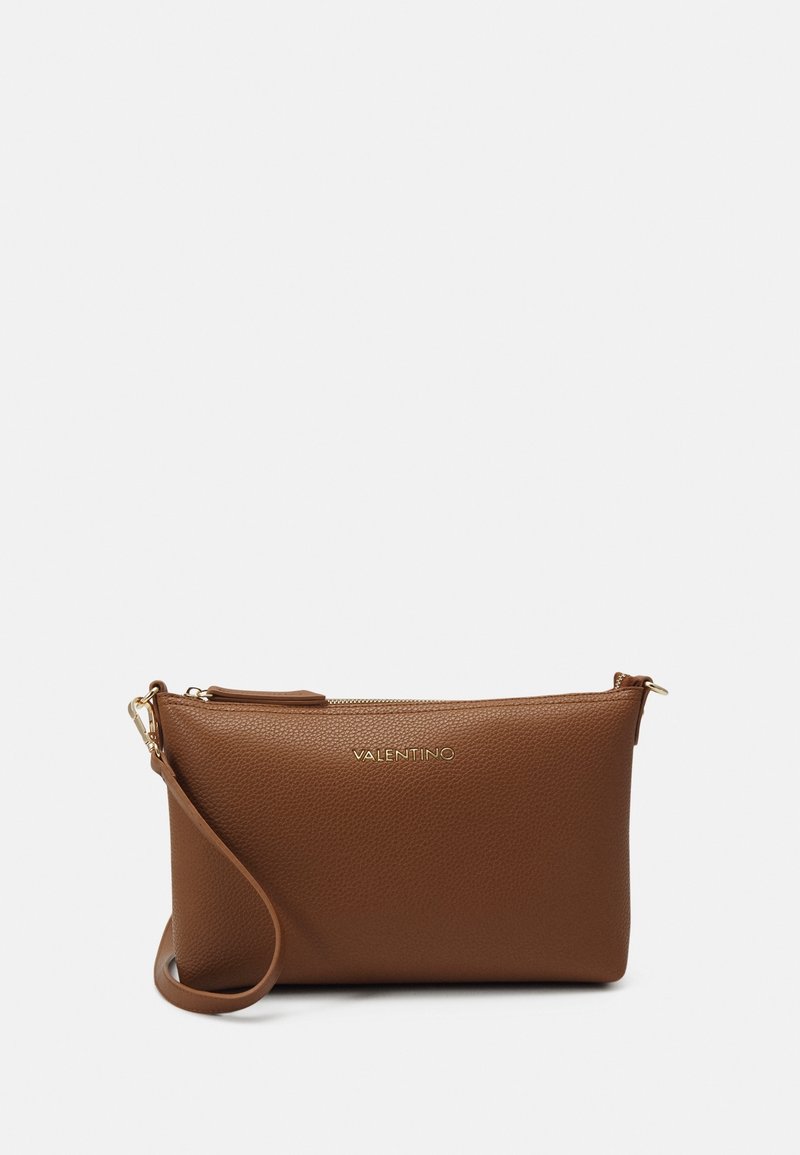 Hnědá kožená kabelka na ruku s texturovaným povrchem, zlatými zipy a odnímatelným popruhem. Na přední straně má decentně vyražené logo.