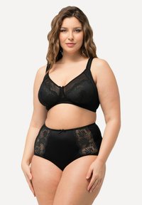 Černý komplet spodního prádla, který zahrnuje průsvitnou bralette se květinovou krajkou a vysokými kalhotkami s krajkovými detaily a mašlí. Hladká textura.