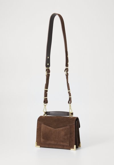 Bolso de ante marrón con un diseño estructurado, que presenta un bolsillo frontal, acentos de hardware dorado y una correa de cuero desmontable.