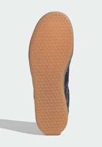Rubber sole with a textured honeycomb pattern. Color is light tan. Side features a floral design in shades of blue, pink, and green.