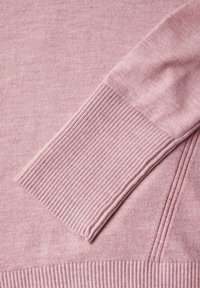 Ljusrosa stickad tröja med ribbade mudd och nederkant, mjuk textur och subtila färgvariationer. Detaljerad sömnadsaccent längs sömmarna.