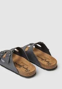 Melni sandales ar korķa zolēm, aprīkotas ar divām regulējamām siksnām ar sudraba sprādzēm. Uz iekšējās zoles ir drukāts teksts "Pepe Jeans London".