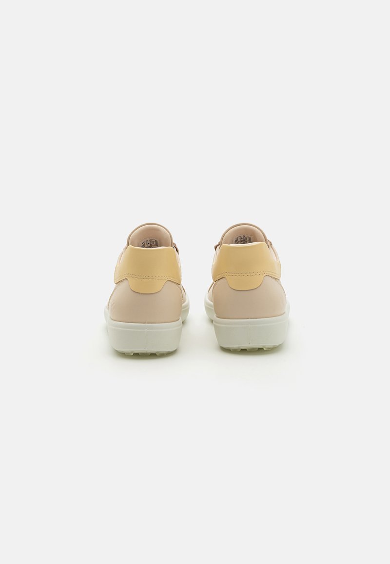 Schuhe mit runder Form, aus beigem synthetischem Material mit einem gelben Absatz und einer weißen Sohle. Glatte Oberfläche, minimalistische Details.