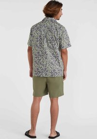 Short-sleeve patterned shirt with green leaf design on gray background, paired with olive green shorts. Smooth fabric, casual fit.