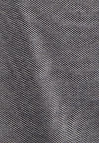 Grijze stof met een gestructureerd patroon van kleine, gelijkmatig verdeelde stippen, die de uitstraling van een lichtgewicht en ademend materiaal weergeeft.