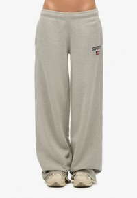Szare, szerokie spodnie dresowe z mieszanki bawełny, z wyhaftowanym logo "Superdry" i drobnym detalem w postaci flagi. Miękka faktura i luźny fason.