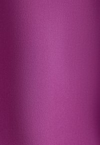 Gros plan d'un tissu lisse et texturé d'une couleur magenta vive unie avec des variations subtiles de lumière.