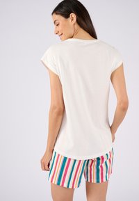 Witte t-shirt met korte mouwen en ronde hals, gecombineerd met multicolor gestreepte shorts met roze, blauwe en gele strepen.