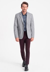 Vaaleanharmaa bleiseri, kukkapaido, viininpunaiset housut ja mustat kengät. Bleiserissä on muotoiltu leikkaus ja viistot läpät.