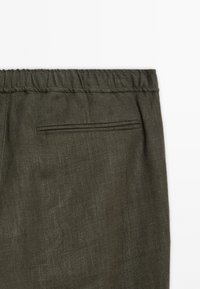 Olive green linen pants featuring a textured finish, elastic waistband, and a single welt pocket on the back.