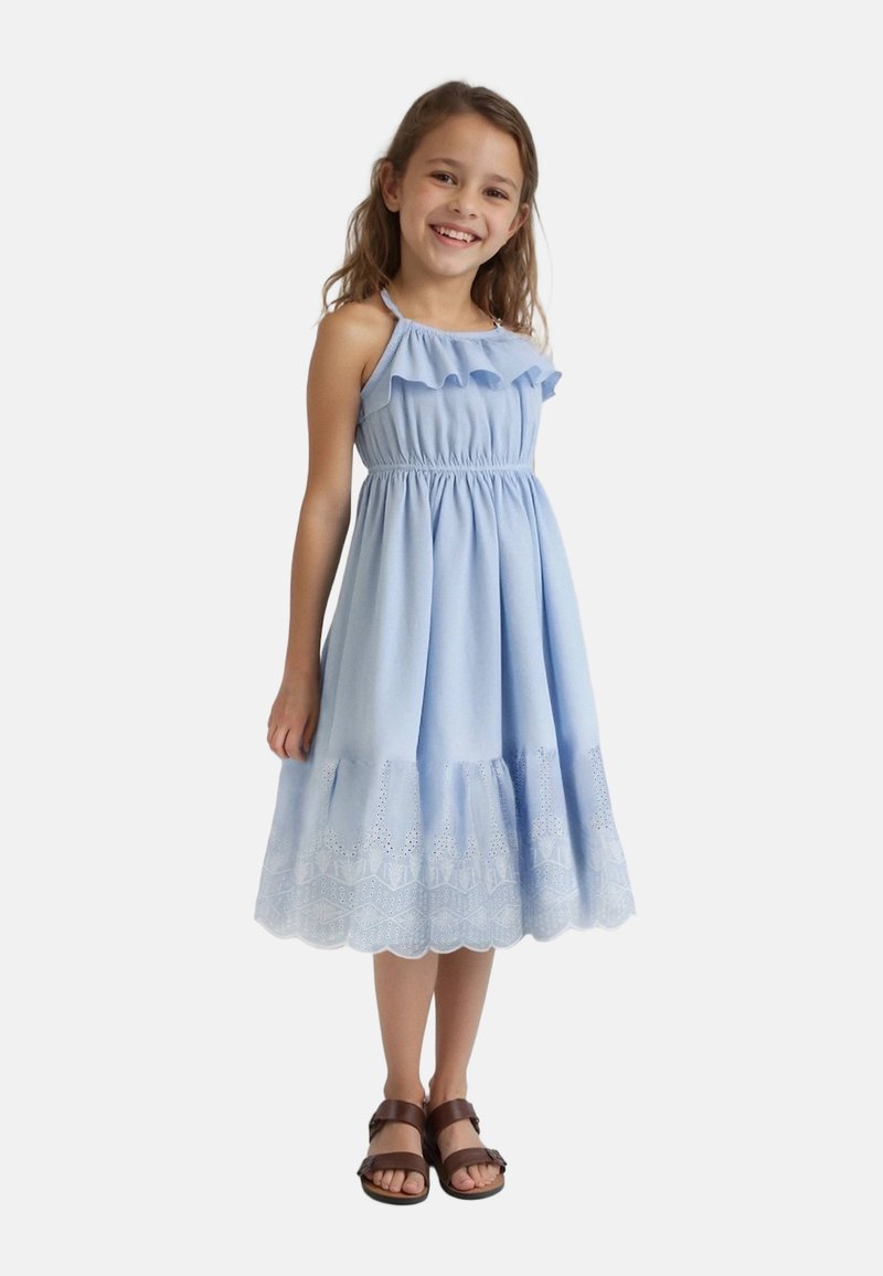 Robe en coton bleu clair avec bretelles froncées, corsage smocké et ourlet festonné orné de dentelle. Associée à des sandales brunes.