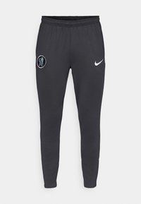 Grå Nike sweatpants med elastisk talje, tapered ben, et Chelsea FC-logo på venstre lår og en kontrasterende hvid Nike swoosh.