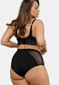 Ensemble de lingerie noir avec un dos en dentelle transparente et une ceinture texturée. Le soutien-gorge possède des bretelles ajustables et une fermeture à crochet.