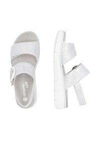 White sandals featuring textured and smooth synthetic straps, a buckle closure, and a white rubber sole with grip patterns.
