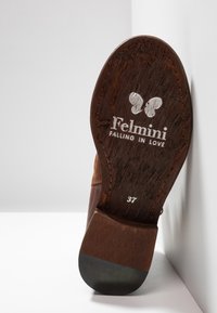 Semelle de chaussure en cuir marron affichant le logo de la marque "Felmini Falling in Love", une icône de papillon et la taille 37 sur fond blanc.