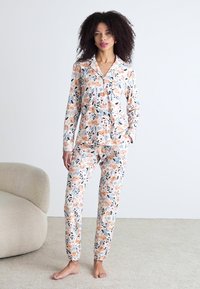 Schlafanzug-Set mit Blumenmuster aus weichem Stoff, bestehend aus einer Knopfleiste-Oberteil und Hosen mit elastischem Bund, in Pfirsich-, Grün- und Schwarztönen.