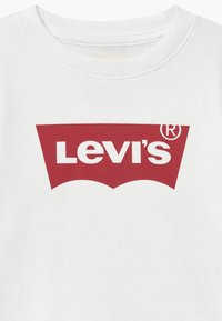 Witte katoenen t-shirt met een ronde halslijn, voorzien van een groot rood Levi's batwing logo in het midden. Zachte textuur met korte mouwen.